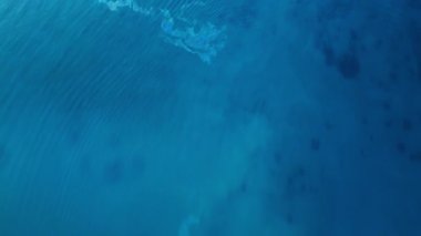 Mavi şeffaf su üzerinde uçuş. Dipteki taşlar gök mavisi suyun içinden görülebilir..