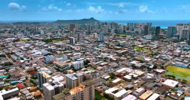 Yoğun mimariyle modern şehrin kentsel alanının üzerinde uçuyor. Düşük katlı binalar, otoparklar ve araba dolu yollar. Honolulu, Hawaii, ABD. Waikiki manzarası ve Diamond Head Krateri.