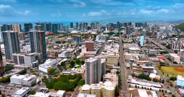 Birçok arabalı düz yollar modern Honolulu, Hawaii, ABD 'nin şehir panoramasını geçer. Pasifik Okyanusu kıyısında arka planda yüksek binalar var. Hava görünümü.