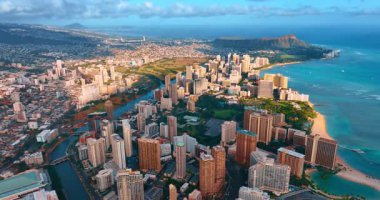 Honolulu 'nun kentsel manzarasında bazı noktalar batan güneşin parlak ışınlarıyla aydınlatılıyor. Günbatımında Waikiki tatil köyünde İHA görüntüleri. Arkaplanda Diamond Head Krateri. Honolulu, Hawaii, ABD.