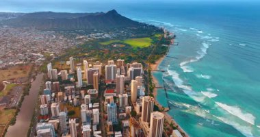 Beyaz köpüklü dalgalar ikonik kumlu plajlara doğru yavaşça akıyor. Honolulu, Hawaii, ABD 'deki Waikiki şehrinin insansız hava aracı görüntüleri. Elmas Başlı Krater ve arkaplan.