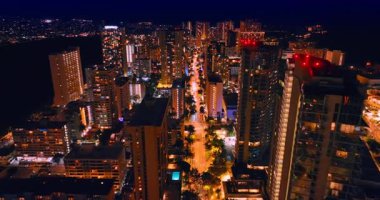 Palmiye ağaçları boyunca uzanan ve farları açık bir sürü araba olan harika aydınlatılmış yolda uçuyorlar. İHA görüntülerinden Waikiki 'nin gece vakti muhteşem manzarası.