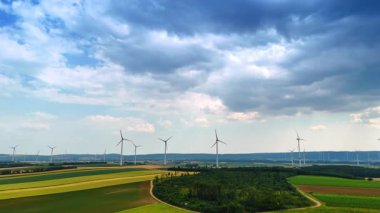 Dönüşümlü rüzgar değirmenleri olan tarım çiftlikleri. Yağmurlu bulutlu hava manzarayı kaplıyor..