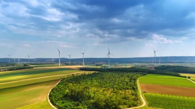 Yel değirmenlerinin yenilenebilir enerji ürettiği görkemli bir kırsal bölge. Rüzgâr çiftliklerinin üstündeki gökyüzünü kaplayan kara bulutlar. Hava görünümü.