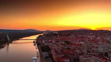 Tuna ve eski şehrin üzerinde turuncu gökyüzü. Slovakya, Bratislava 'nın günbatımı manzarası. Hava perspektifi.