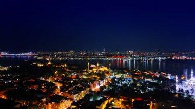 Gece şehrin ışığı, karanlık suları yansıtır. İstanbul, Türkiye 'nin havadan görünüşü. Şehir manzarasında muhteşem aydınlatılmış camiler..