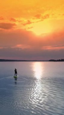 Ayağa kalk, Sörf tahtası adam silueti. Genç adam günbatımında kürek tahtasında egzersiz yapıyor.