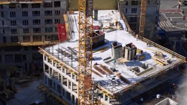 Yüksek binaların inşaatı sürüyor. İşçiler, gündüz saatlerinde turnalarla çevrili kentsel bir alanda yüksek binalar inşa ediyorlar..