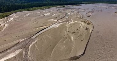 Nehrin kumlu dibinde kurumuş. Drone 'dan görüntüler. Çevrede kocaman yeşil ağaçlar yetişiyor. Alaska 'nın göz kamaştırıcı dağları.