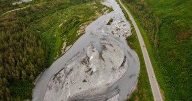 Nehrin kurumuş deltasının üzerinde uçuyor. Resimli vadideki nehir boyunca otoban boyunca çok az araba hareket ediyor. Arkaplanda muhteşem dağlar. Alaska.