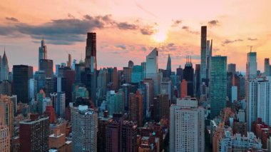 New York şehir merkezinin üzerinde çeşitli binaların üzerinde uçuyorlar. Gün batımında Manhattan 'ın manzarası.