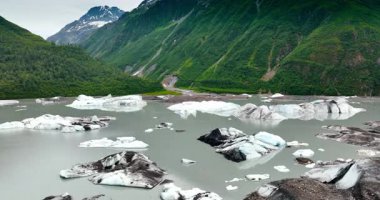 Nehrin üzerinden uçarken, üzerinde kocaman buz parçaları vardı. Rıhtımda yeşil yamaçları olan güzel dağlar. Alaska doğası.