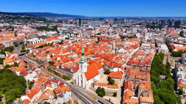 Slovakya 'nın Bratislava kentindeki kilisenin kulesine yaklaşıyoruz. Şehrin tarihi kısmında turuncu çatıları olan çok sayıda bina. Hava görünümü.