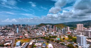 Honolulu, Hawaii, ABD şehir manzarası boyunca yoğun trafiği olan çok şeritli bir yol. Şehrin üzerinde mavi gökyüzünde kabarık bulutlar.