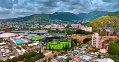 Honolulu 'daki Hawaii Üniversitesi stadyumlarına yaklaşıyoruz. Arkaplanda yeşil dağların üzerinde dramatik bulutlar var. Hava perspektifi.