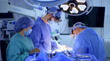 Cerrahlar ameliyathanede ameliyat eder. Cerrahlar ve sağlık personeli, modern bir ameliyathanede, hasta bakımı ve güvenliğini sağlama amaçlı cerrahi bir prosedüre odaklanıyorlar..