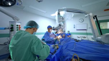 Modern cerrahi prosedür işliyor. Cerrahlar ileri düzey tıbbi teknolojinin altını çizerek yüksek teknolojili bir cerrahi odada hassas bir operasyon gerçekleştiriyorlar..