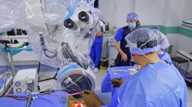 Karmaşık operasyonlarda cerrahlar. Mavi önlüklü tıbbi ekip, parlak bir ameliyathanede gelişmiş ekipman kullanarak hassas bir ameliyat yapar..