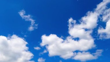 Bulutlar hareket halinde. Bulutlar parlak mavi bir gökyüzünde pürüzsüz bir zaman diliminde sürükleniyor ve havanın dinamik doğasını yakalıyor..