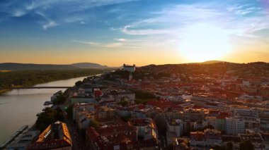 Batan güneş Bratislava, Slovakya 'nın manzarasını aydınlatıyor. Eski kasabanın ve Tuna Nehri 'nin üzerinde gün batımında İHA görüntüleri..