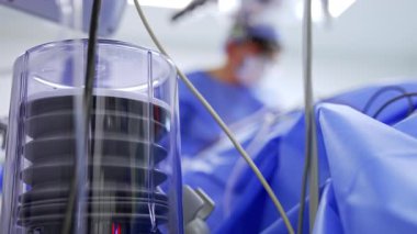 Akciğer solunum cihazının pompası çalışıyor. Kapatın. Doktorlar bulanık arkaplanda ameliyat yapıyorlar.