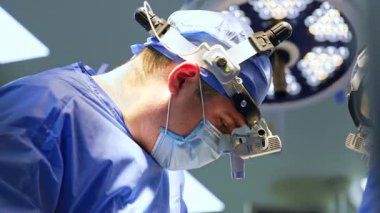 Cerrahi hoparlörlerdeki beyaz erkek cerrah ameliyatta. Yan görünüm, nörocerrahın işini yaparken çekilmiş portresi..