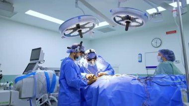 Ameliyatın yapıldığı ameliyathanedeki ameliyat masasına yaklaşıyoruz. İki erkek beyin cerrahı işbirliği içinde ameliyat yapıyor..