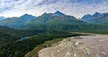 Verdant dağlarının eteğinde kurumuş nehirden oluşan geniş bir delta. Manzaranın üzerindeki bulutlu gökyüzü. Alaska vahşi doğası.