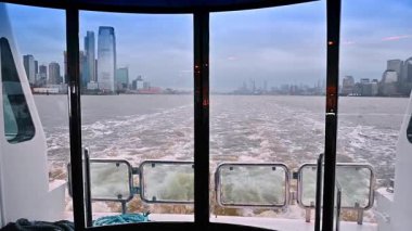 Gri sıkıcı bir günde New York 'ta nehir kıyısında seyahat etmek. Çalkantılı su manzarasında, teknenin arkasındaki pencereden bir manzara..