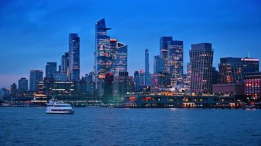 Günbatımında New York 'un modern mimarisi rıhtımda. Bir nehir teknesi su manzarası boyunca seyahat eder..