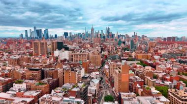 Geleneksel kentsel alandan çok katlı binalarla caddenin üzerinde uçmak. Modern Manhattan 'ın ufuk çizgisi, arka planda dramatik bulutlar altında.