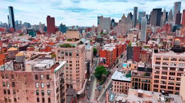 Tepesinde yeşil dinlenme yerleri olan apartman bloklarının üzerinden uçun. Manhattan binaları arka planda. New York, ABD hava manzaralı.