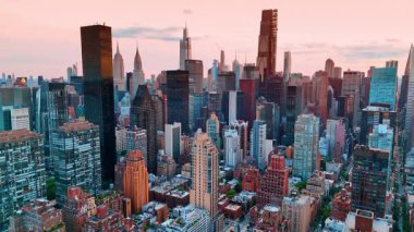 ABD 'nin New York şehir merkezinden yükseliyor. Manhattan gökdelenlerinin tepeleri Gün batımında pembe gökyüzünün zemininde.