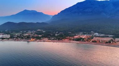 Türkiye 'nin Kemer sahil beldesinin günbatımındaki manzarası. Etrafı dağlarla çevrili yeşil bir kıyı..