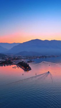Deniz kıyısının güzel rıhtımına yaklaşıyoruz. Dağ siluetleri arka planda. Hava görüntüsü. Dikey video.