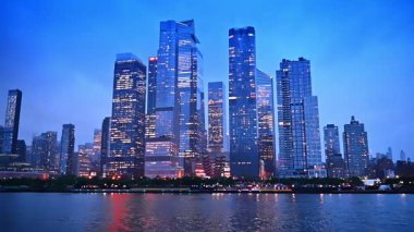 Modern New York 'un göz kamaştırıcı modern mimarisi. Pencereleri açık. Alacakaranlıkta nehirden alçak açı görünümü.