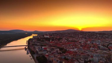 Gün batımında inanılmaz turuncu gökyüzü nehir ve şehrin üzerinde. Slovakya 'nın Bratislava kentindeki hava perspektifi.