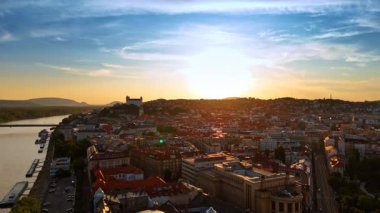 Batan güneş, Slovakya 'nın Bratislava kentinin manzarasını kamaştırıyor. Tuna kıyısı üzerinde İHA uçuşu.