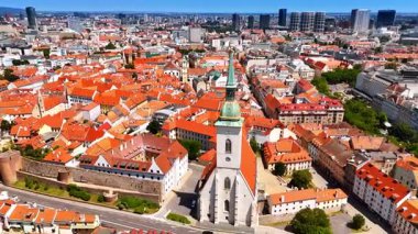 Eski kasabanın turuncu çatılı mimarisinin önünde duran kilise binası. Bratislava, Slovakya 'nın tarihi kısmının güneşli manzarası. Hava görünümü.