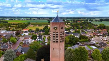 Üzerinde rüzgar horozu olan bir saatle tuğla kulede uçmak. Hollanda, Vierlingsbeek 'teki Saint Lawrence Kilisesi..
