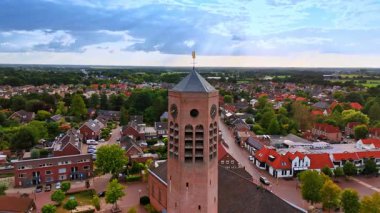 Kilisenin yüksek tuğlalı kulesinden, tepesinde rüzgar horozu olan bir kuleden uzakta. Hollanda 'nın manzarası arka planda..