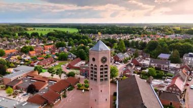 Aziz Lawrence Kilisesi 'nin tepesinde rüzgar horozu olan kulesi. Arkaplanda yeşil şehir manzarası var. Vierlingsbeek, Hollanda. Hava görünümü.