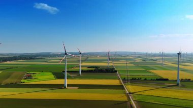Yeşilin farklı tonlarında güzel tarlalar. Rüzgar türbinleri rüzgarda yavaşça döner. Hava görünümü.