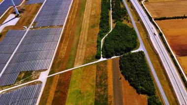 Sıcak ve güneşli bir günde kahverengi tarlaların üzerindeki görüntüler. Bölgeden geçen güneş panelleri, rüzgar türbini ve otoyollara bakın.