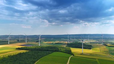 Uçsuz bucaksız tarlaların üzerini rüzgar türbinleriyle kaplayan dramatik bulutlar. Yeşil enerji üretimi için kullanılan kırsal alana hava perspektifi.
