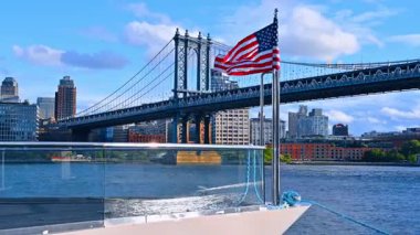 Teknenin ön tarafında Amerikan bayrağı dalgalanan bir rüzgar var. New York, ABD 'deki Manhattan Köprüsü' nün alçak açılı görüntüsü..