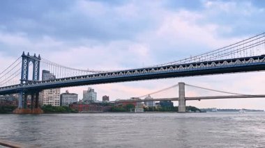 Tren Manhattan Köprüsü 'nden geçiyor. Su manzarasından alçak açı. Brooklyn Köprüsü, arka planda. New York, ABD.