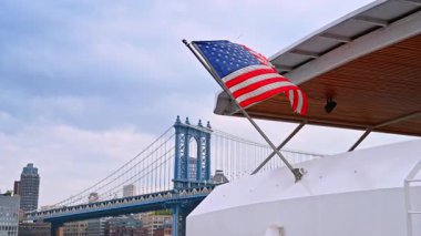 Modern teknede dalgalanan Amerikan bayrağı. Arkaplanda Manhattan Köprüsü.