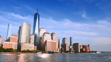 Parlak güneş modern yüksek binaların cephelerini aydınlatıyor. Nehir manzarasından New York mimarisinin alçak açılı görüntüsü.