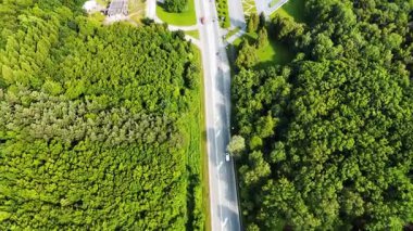 Ormandaki otoyolun havadan görünüşü. Havadan bakıldığında, yemyeşil ormanı kesen bir otoyol görünüyor. Yakınlarda modern bir yapı var..